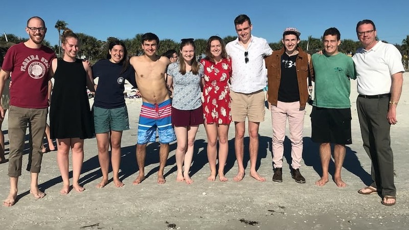 Ten members of the 2019 choir standing on a beach in Florida.